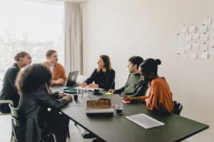 Um grupo de seis pessoas de diferentes etnias em torno de uma mesa de escritório.